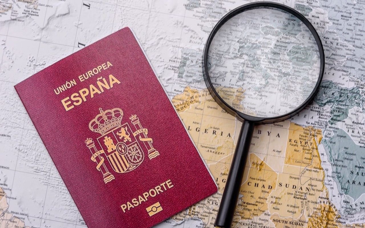 Un pasaporte sobre un mapa del mundo, junto a una lupa y unos billetes.