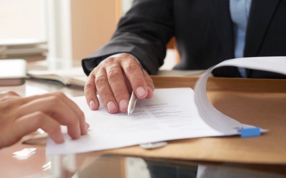 Unas manos firman un contrato sobre la mesa.